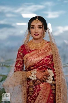 a woman in a red and gold bridal outfit with her hands on her hips