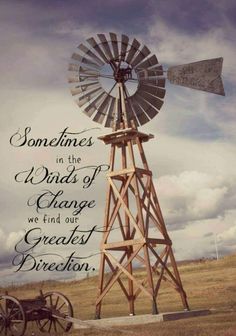 a wooden windmill sitting in the middle of a field with a quote on it that reads, sometimes in the winds of change we find our greatest direction