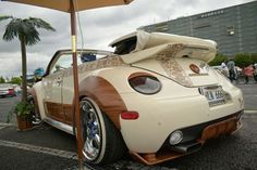 an unusual car is parked in the parking lot with its hood up and surfboard on top