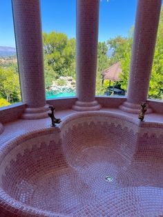 a large round sink in front of a window with columns on both sides and a pool behind it