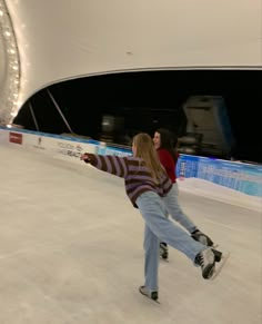 two people skating on an ice rink at night