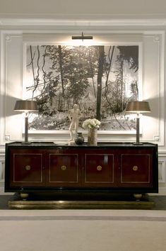 a living room with two lamps and a large painting on the wall above it's console table