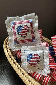 three red, white and blue patriotic heart pillows in a wicker basket on a table