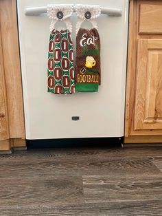 two towels hanging from the handle of a dishwasher in front of wooden cabinets