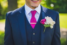 a man in a suit with a pink tie and flower boutonniere on his lapel