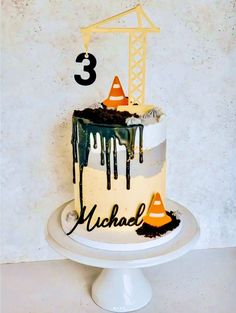 a three tiered cake decorated with construction equipment and the number 3 on it's side