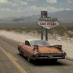 an old car is driving down the road in front of a sign that says las vegas