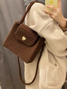 a woman is taking a selfie with her cell phone while wearing a knitted bag