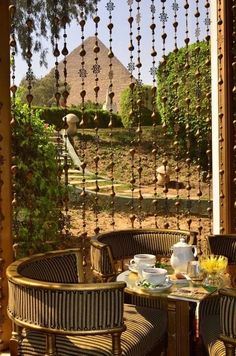 two wicker chairs sitting on top of a patio next to a table with food