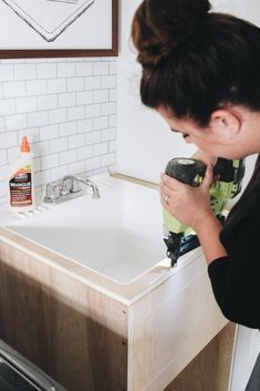 a woman using a power drill to fix a sink