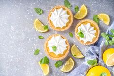 three lemon pies with fresh mint leaves and sliced lemons next to them on a gray surface