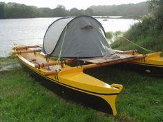 two yellow canoes sitting next to each other on the grass near a body of water