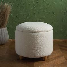 a white ottoman sitting on top of a wooden table next to a potted plant