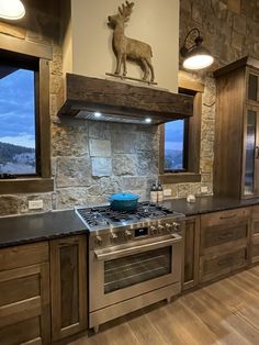 a kitchen with an oven, stove and counter top in front of a stone wall