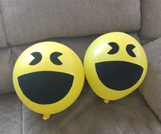 two yellow balloons with faces drawn on them sitting on a couch next to each other