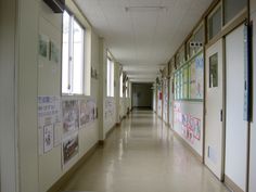 a long hallway with posters on the wall and windows in each room, leading to other rooms