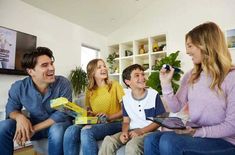 a group of people sitting on top of a couch talking to each other in a living room