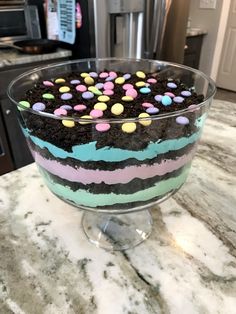 a cake in a glass dish with chocolate and candy toppings on the top is ready to be eaten