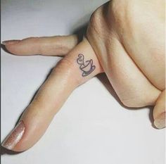 a person's hand with a small anchor tattoo on their left thumb and finger