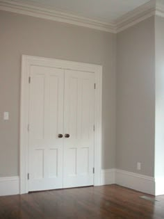 an empty room with white doors and hard wood floors