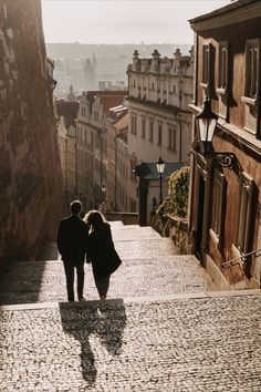 two people are walking down an old cobblestone street