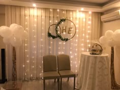 two chairs are set up in front of a table with balloons and wreaths on it