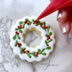 a hand holding a red pen over a decorated cookie