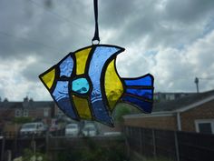 a stained glass fish hanging from a window