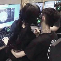 two people wearing headphones sitting in front of computer monitors with green lights on their ears