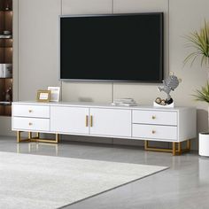 a large flat screen tv mounted on the wall in a living room with white furniture