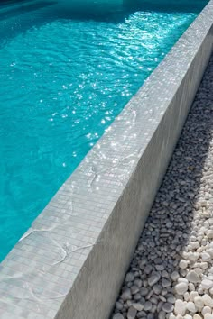 an empty swimming pool with rocks and stones on the edge, next to it's water