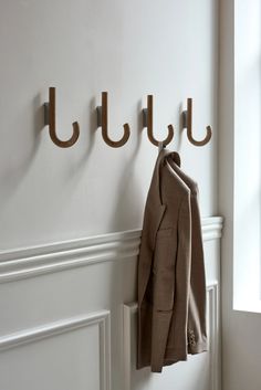 coat hangers are hanging on the wall next to a coat rack with two coats