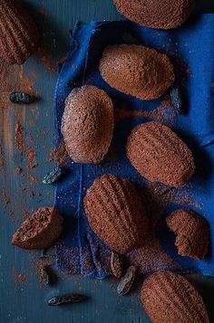 chocolate cookies are on a blue cloth next to some nuts