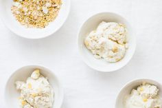 three white bowls filled with different types of ice cream on top of a white table