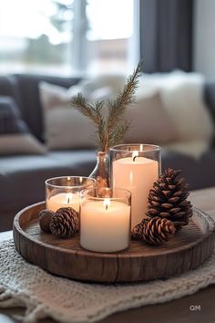 some candles are sitting on a tray with pine cones