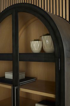 two white vases sitting on top of wooden shelves