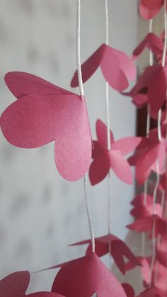 some pink paper hearts hanging from strings