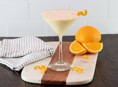 an orange slice is sitting on a cutting board next to a martini glass and napkin