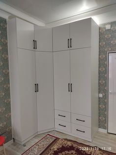 a room with white cupboards and rug on the floor in front of wallpapered walls