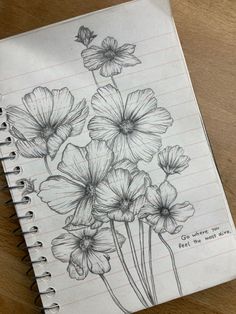 pencil drawing of flowers on lined paper with notepad and pen sitting next to it