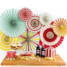 some paper fans are hanging on the wall above a table with snacks and beer bottles