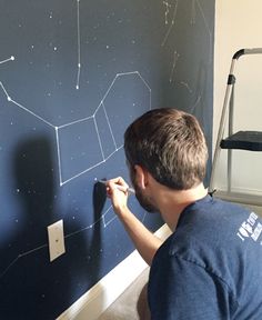 a man is painting a wall with stars on it