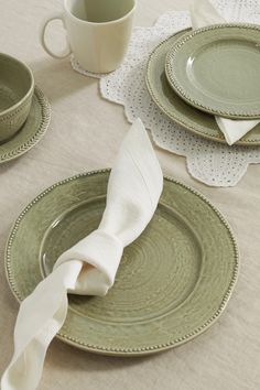 the table is set with plates, cups and napkins