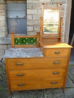 an antique dresser with marble top and mirror on it's side, in front of a brick building