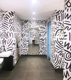 a long hallway with black and white wallpaper on the walls that has graffiti written all over it