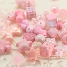 there are many pink and white items on the table together, including buttons and beads