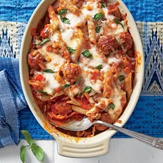 a casserole dish with meat, cheese and tomato sauce on a blue cloth