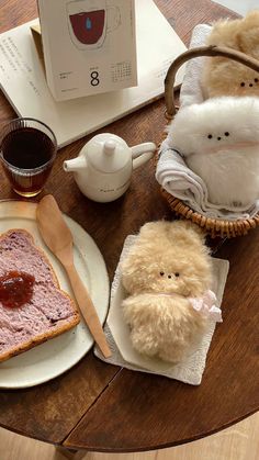 two small stuffed animals sitting on top of a table next to bread and coffee cup