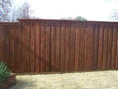 a brown wooden fence next to a brick planter