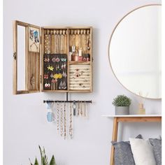 an open wooden box with jewelry hanging from it's sides next to a mirror